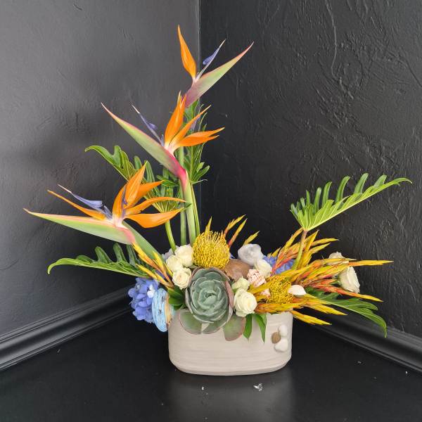 Tropical arrangement with bird of paradise flowers in a white vase