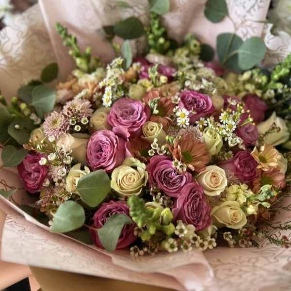 Bouquet of pink and cream roses with small white filler flowers