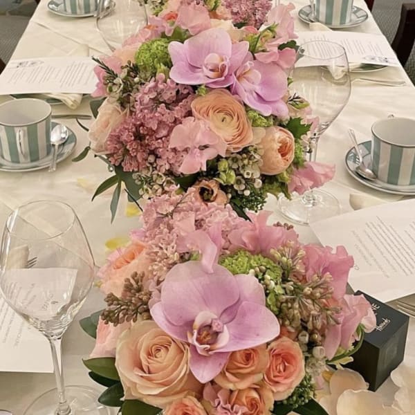 Pink and peach floral centerpieces line a long wedding table