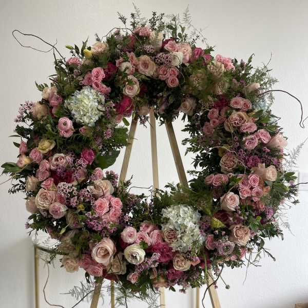 Large pink floral wreath on a wooden stand
