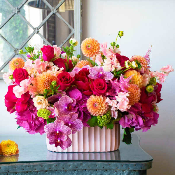 Bright mixed flower arrangement in a pink ribbed container
