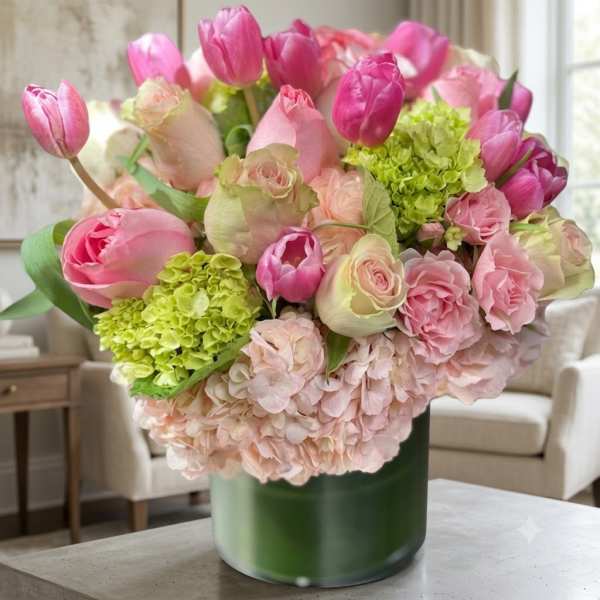 Pink tulips and roses arranged with hydrangeas in a green vase