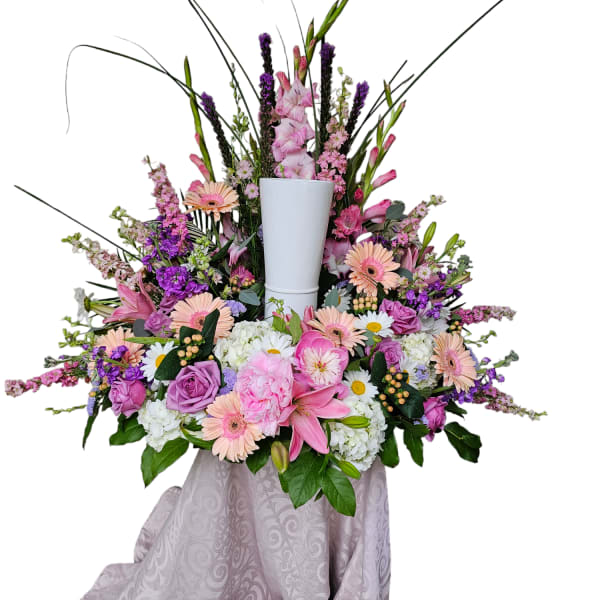 Large pink and purple floral arrangement in a white pedestal vase