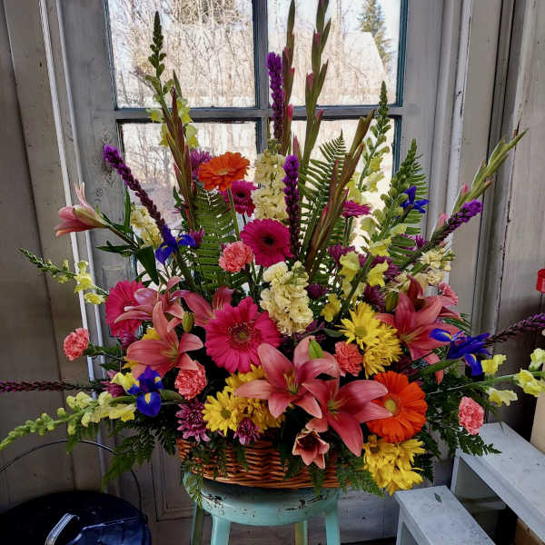 Large mixed flower arrangement in a wicker basket with lilies and gerbera daisies