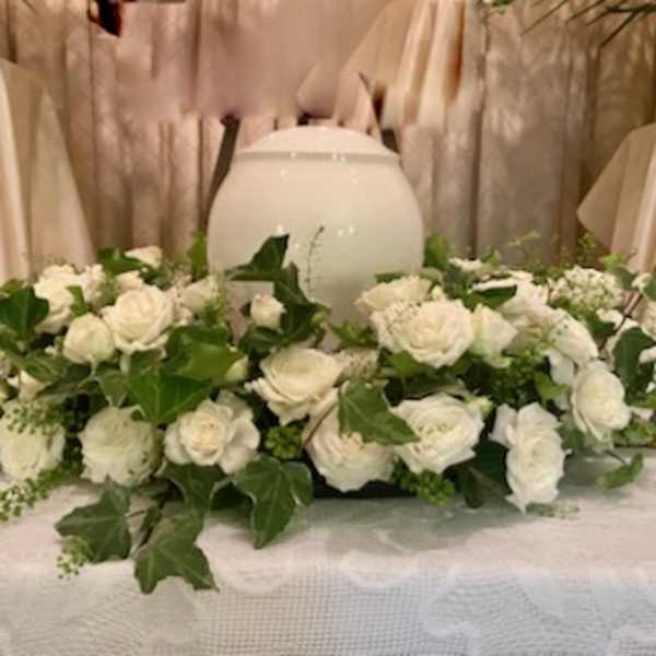 White rose arrangement around a white urn