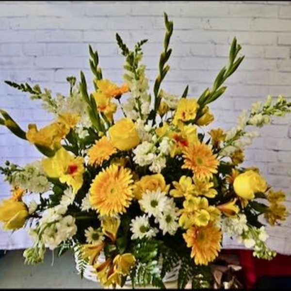 Large yellow and white floral arrangement with tall stems in a basket