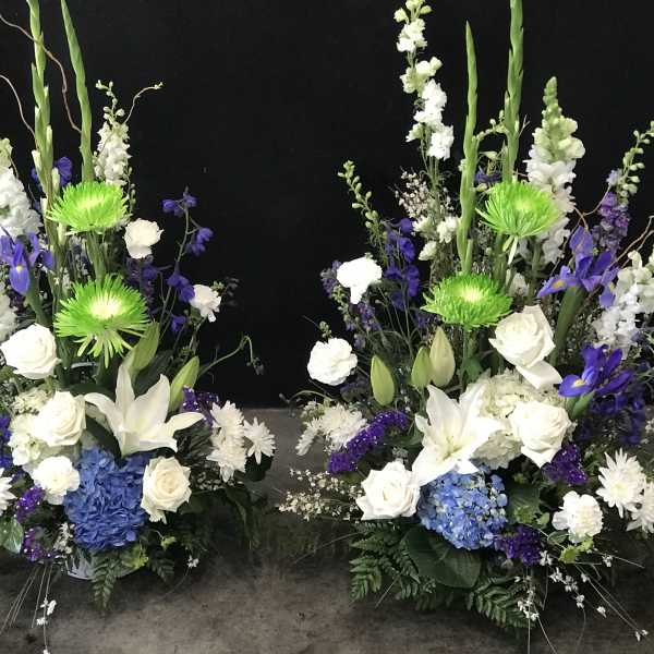 Two tall floral arrangements with white, blue, and purple blooms