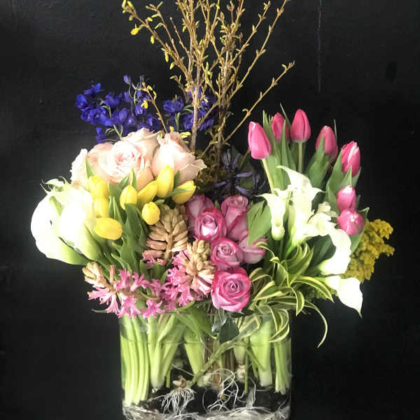 Mixed bouquet in a clear glass vase with tulips, roses, calla lilies, and orchids