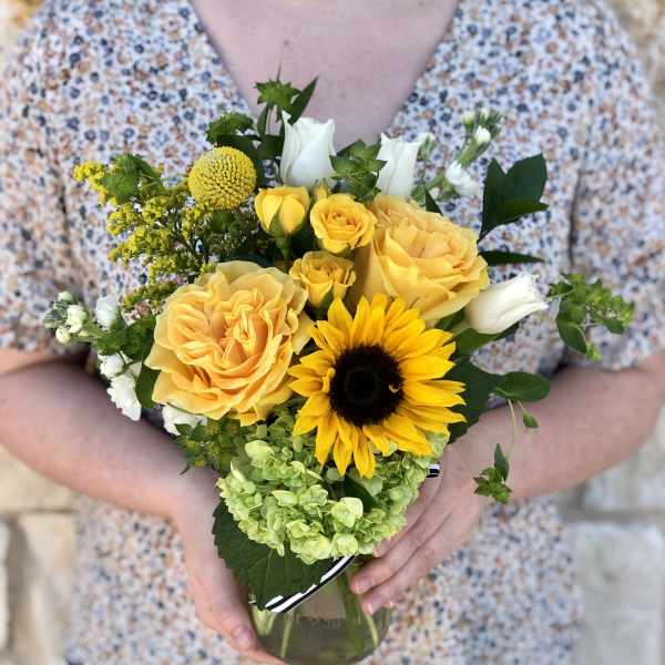 Yellow roses and a sunflower in a glass vase