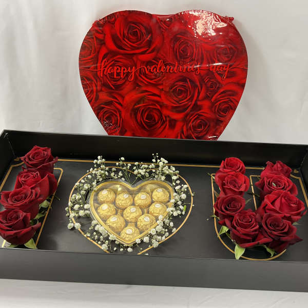 Red roses and chocolates arranged in a black gift box with a heart lid