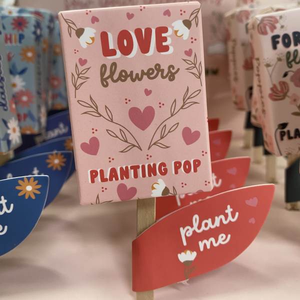 Pink plant marker with hearts and the words "Love flowers"