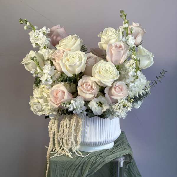 Arrangement of white and blush roses with white hydrangeas in a white ribbed vase