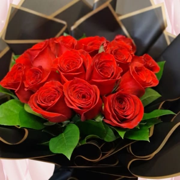 Bouquet of red roses wrapped in black paper with gold trim