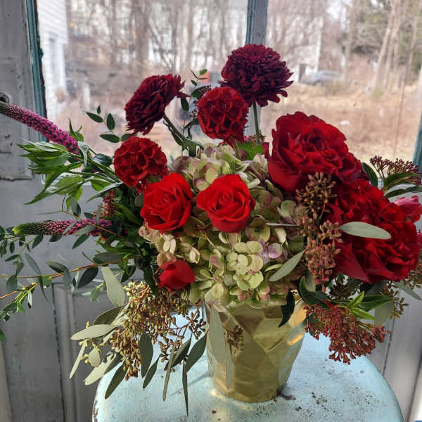 Red roses and burgundy blooms in a gold vase