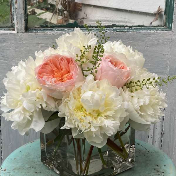 Pink and white flowers arranged in a square glass vase