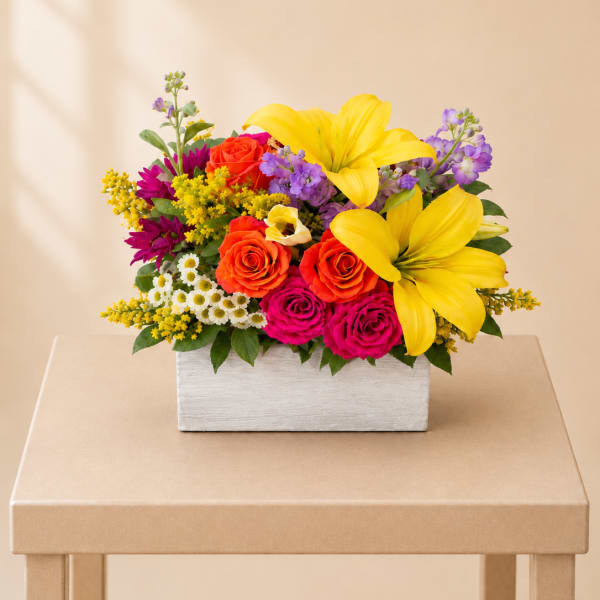 Bright mixed bouquet in a white rectangular box with yellow lilies and roses