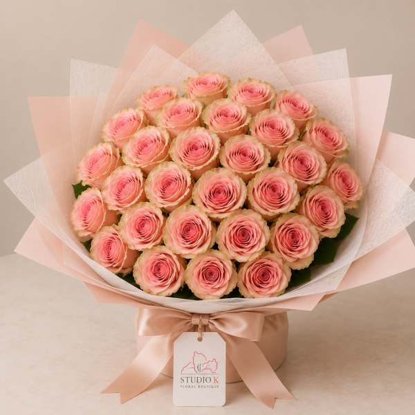 Bouquet of pink roses wrapped in pale pink and white paper with a satin ribbon