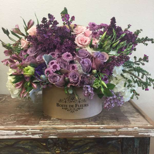 Lavender and pink floral arrangement in a round box