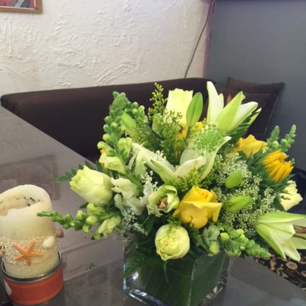 Yellow and white floral arrangement in a square glass vase