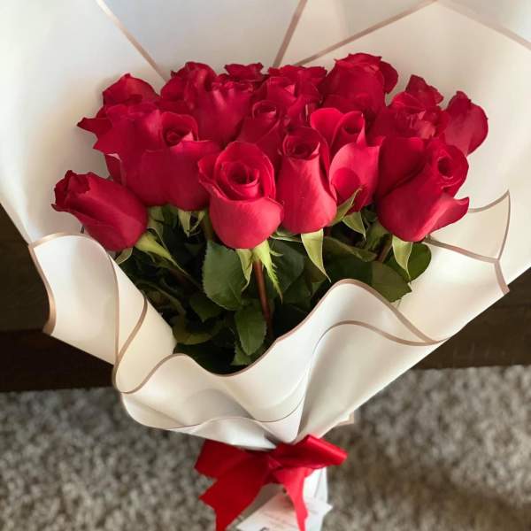 Bouquet of red roses wrapped in white paper with a red ribbon