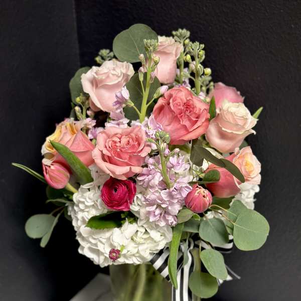 Pink and white bouquet in a clear glass vase with a striped ribbon