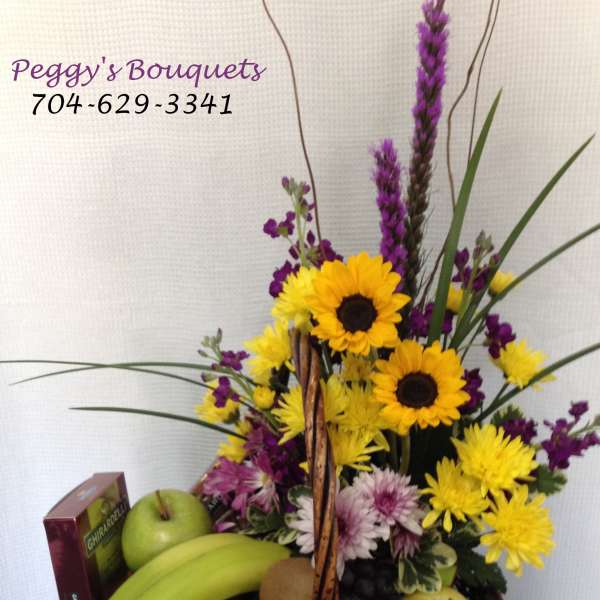 Fruit basket with sunflowers and purple flowers in a wicker basket