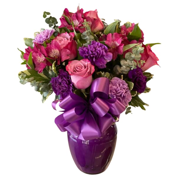 Pink and purple bouquet in a purple vase with a large ribbon