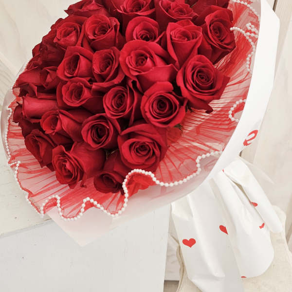 Bouquet of red roses wrapped in white and red paper