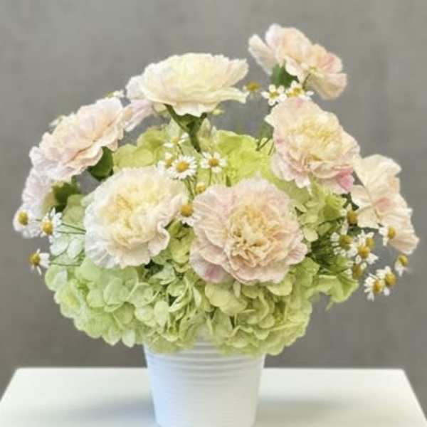 Pastel flower arrangement in a white pot with pale pink blooms and green hydrangeas