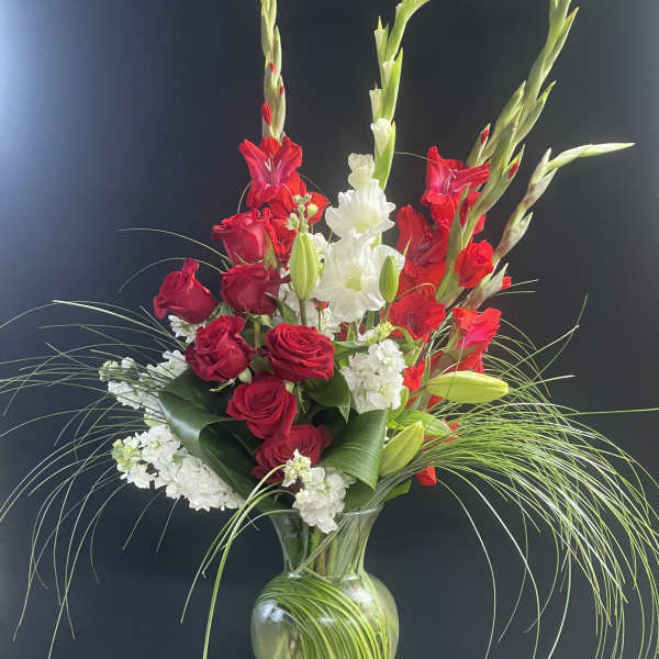 Red roses and white flowers in a clear glass vase with tall green stems