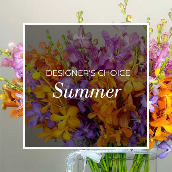 Mixed orange, purple, and pink orchids in a clear vase with a white ribbon