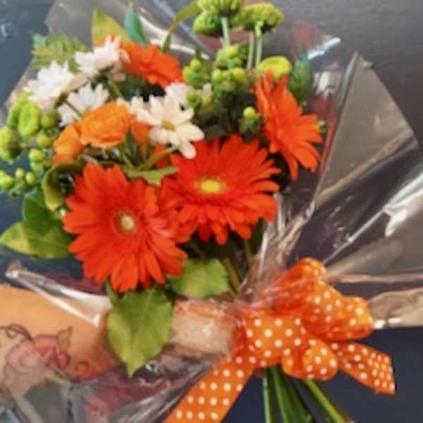 Bouquet of orange gerbera daisies and white daisies with an orange polka-dot ribbon