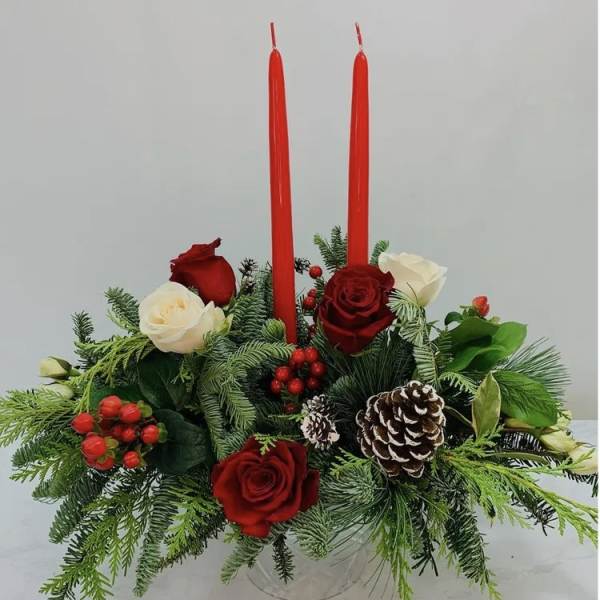 Red and white roses with evergreen foliage and two red taper candles