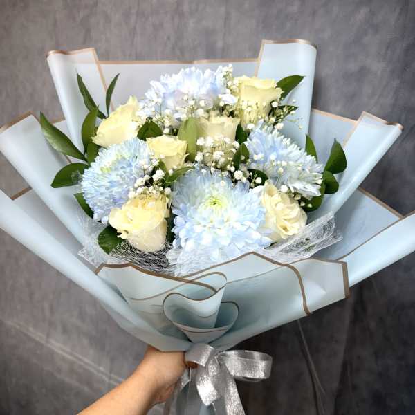 Bouquet of pale blue chrysanthemums and cream roses wrapped in light blue paper