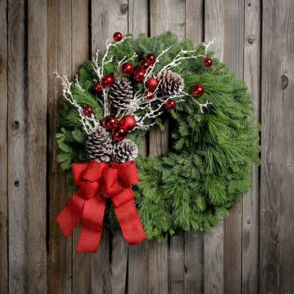 Christmas wreath with pinecones, red ornaments, and a red bow