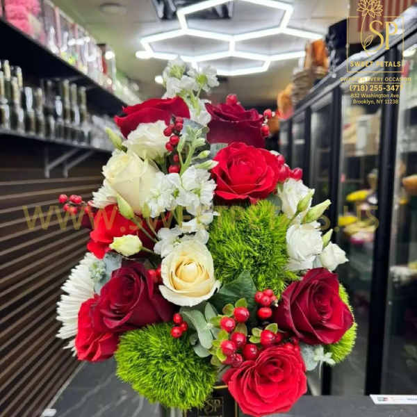 Red and white roses arranged in a metal vase with green pom-pom accents.