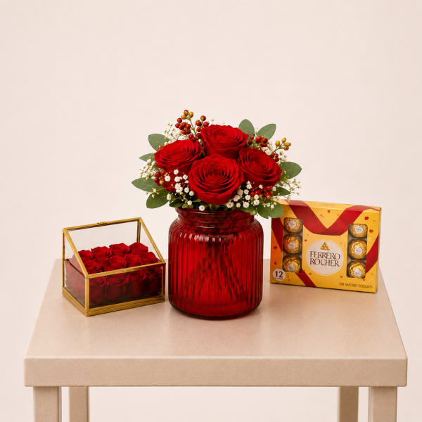 Red rose arrangement in a red vase with chocolates and a rose box