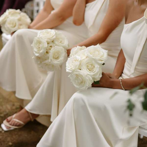 White rose bouquets held by women in white dresses