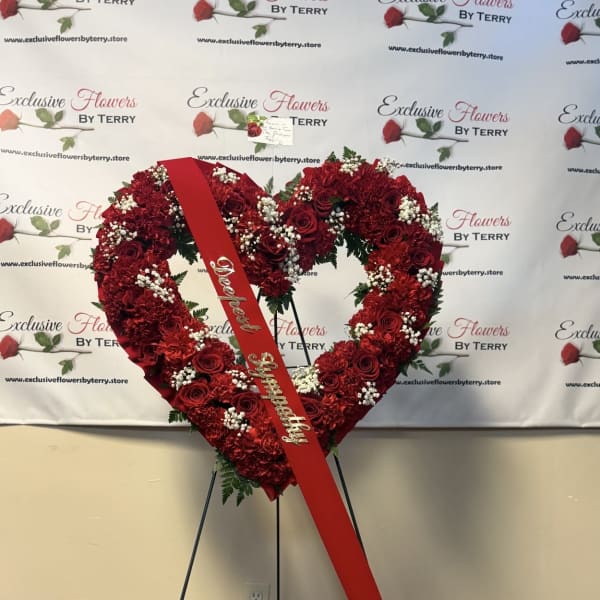 Heart-shaped red floral standing spray with a red ribbon on an easel