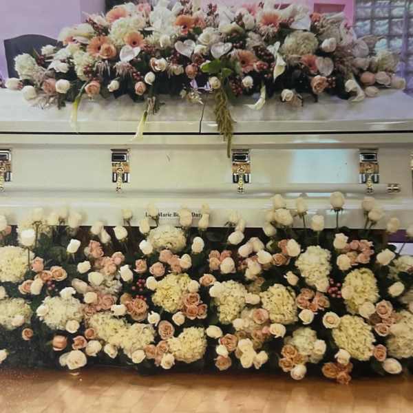 Two flower-covered caskets with white and peach blooms