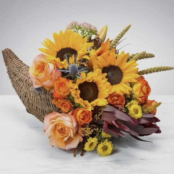 Bouquet of sunflowers and orange roses in a woven horn-shaped basket