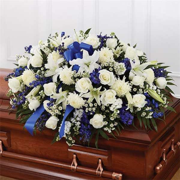 White and blue floral spray on a wooden casket
