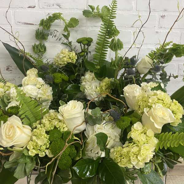 Large green and white floral arrangement with roses and hydrangeas