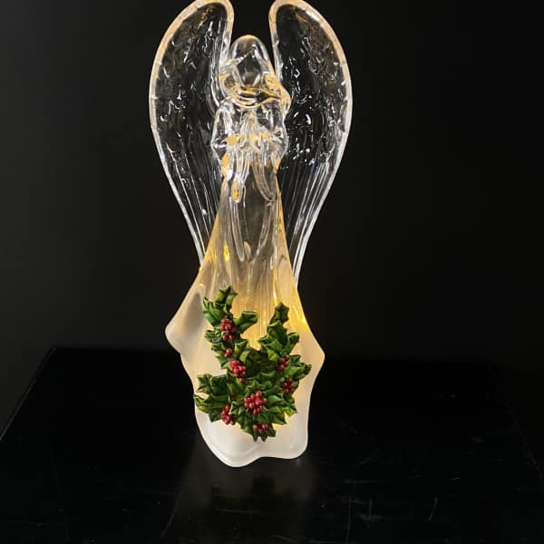 Glass angel figurine with holly decoration on a black background