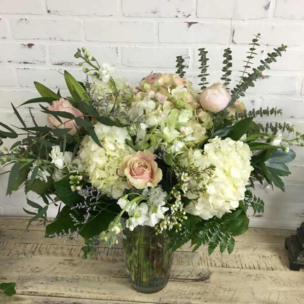 Large bouquet of pale hydrangeas and blush roses in a glass vase