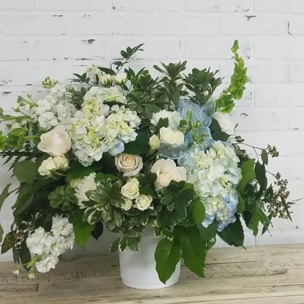 White and pale blue floral arrangement in a white vase