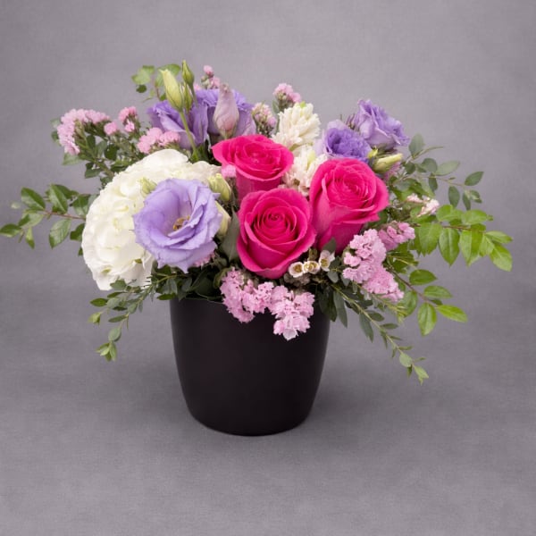 Pink and lavender roses arranged in a black vase