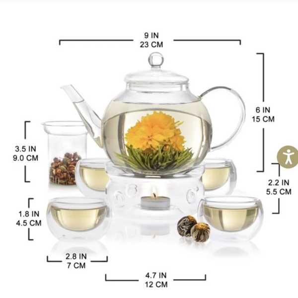 Glass teapot with a yellow flower blooming inside, surrounded by matching cups
