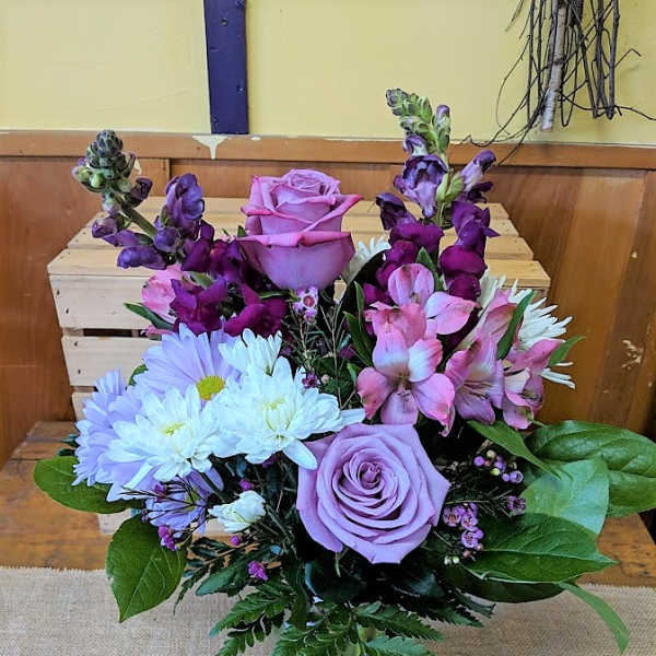 Lavender roses with white daisies and pink-purple blooms in a vase