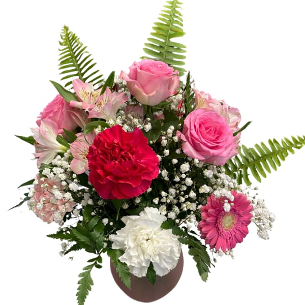Pink roses, carnations, and a gerbera daisy in a round vase